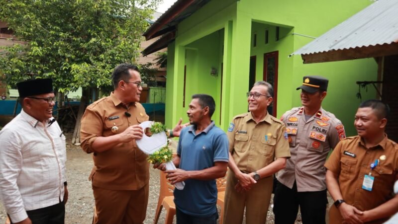 Pj Bupati Pidie Jaya T. Ahmad Dedek menyerahkan kunci rumah kepada Saiful Azhar ( tengah )  Penerima bantuan rumah dari Baitul Mal Pidie Jaya, Selasa, 14/1/2025