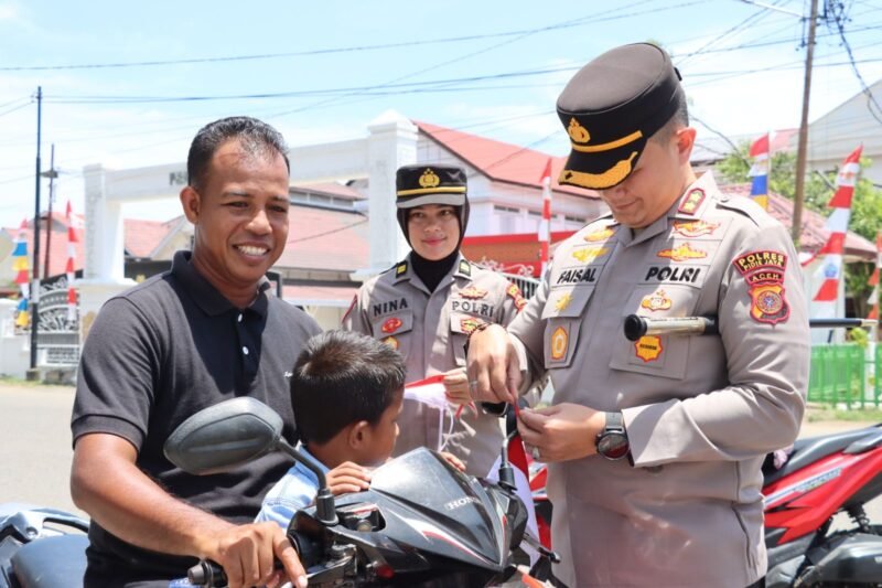 Kapolres Pidie Jaya AKBP Ahmad Pasaribu SH SIK MH, di dampingi Kasi Humas Iptu Nina Ervianti, SH. MH dalam. Kegiatan bagi bagi Bendera Merah Putih dalam menyemarakan HUT RI ke 80. Kamis (14/8/2025). Foto: Dok/Muhammad Rissan 