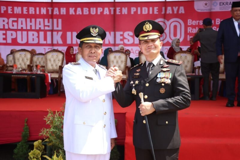 Salam Komando dalam semangat Nasionalisme, Bupati Pidie Jaya Tgk. H. Syibral Malasyi MA., S. Sos., ME ( baju putih ) dengan Kapolres Pidie Jaya AKBP Ahmad Pasaribu, SH., S.I.K., MH, Lapangan Bola Kaki Kota Meureudu, Minggu (17/8/2025). Foto:Dok/ Humas Polres Pidie Jaya