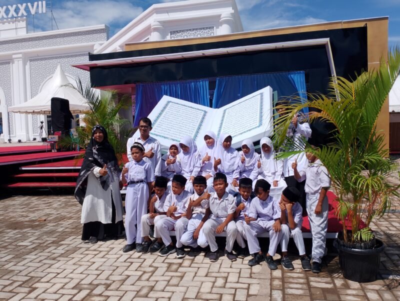 Murid dan Guru MIN 7 Leung Putu, Bandar Baru Berkesempatan bersua Foto Di replika Mushaf Al-Qur'an, Panggung utama MTQ Aceh ke 37, Komplek perkantoran Cot Trieng, Selasa ( 4/11/2025). Foto:Dok/Muhammad Rissan 