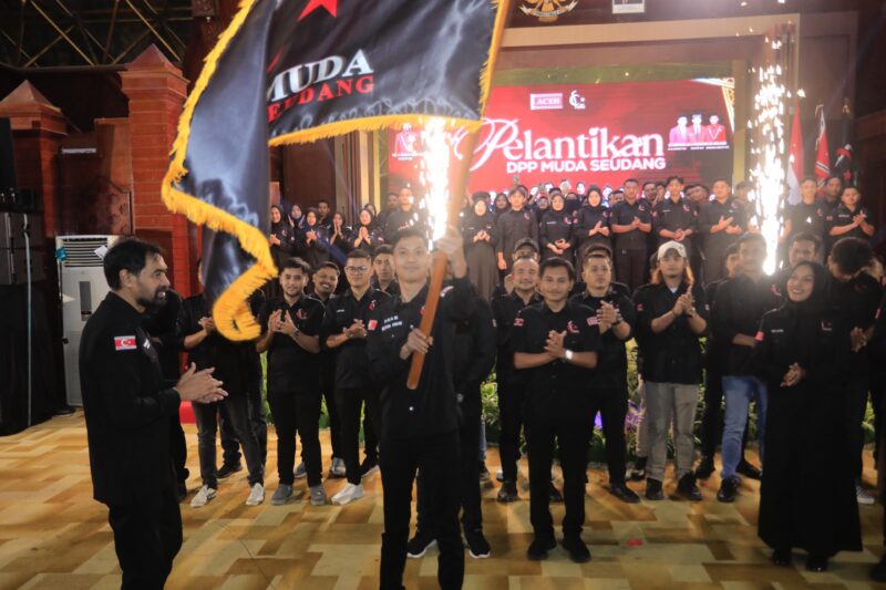 Ketua Umum DPP Muda Seudang terpilih, Agam Nur Muhajir, mengibarkan bendera pataka organisasi usai diserahkan oleh Mualem pada momen pelantikan yang berlangsung di Anjong Mon Mata, Kompleks Meuligoe Gubernur Aceh, Sabtu (18/04/2026) malam.