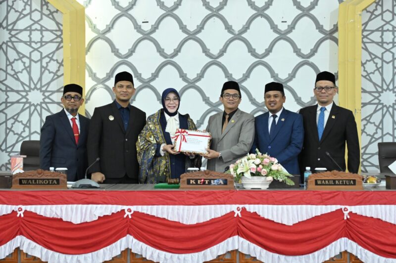 Wali Kota Banda Aceh, Illiza Sa’aduddin Djamal, didampingi Wakil Wali Kota, Afdhal Khalilullah Mukhlis dan Sekda Kota Jalaluddin menyerahkan dokumen RKUA PPAS Perubahan APBK Banda Aceh 2026 kepada Pimpinan DPRK Banda Aceh, yaitu Ketua DPRK Banda Aceh, Irwansyah ST, didampingi dua wakil ketua, Daniel Abdul Wahab dan Musriadi Aswad, dalam sidang paripurna yang berlangsung di Gedung DPRK setempat, Senin (24/8/2026) pagi. Foto: Dok. DPRK Banda Aceh