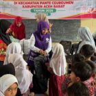 Ketua Posyandu Kabupaten Aceh Barat, Afrinda Novalia, menyerahkan bantuan perlengkapan sekolah kepada siswa terdampak bencana hidrometeorologi di SDN Alue Lhok, Kecamatan Pante Ceureumen, Kamis (29/10/2026). Foto: Dok. Istimewa 